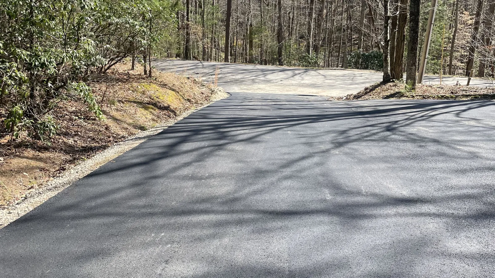 Wide asphalt driveway and turnaround finished on a wooded lot