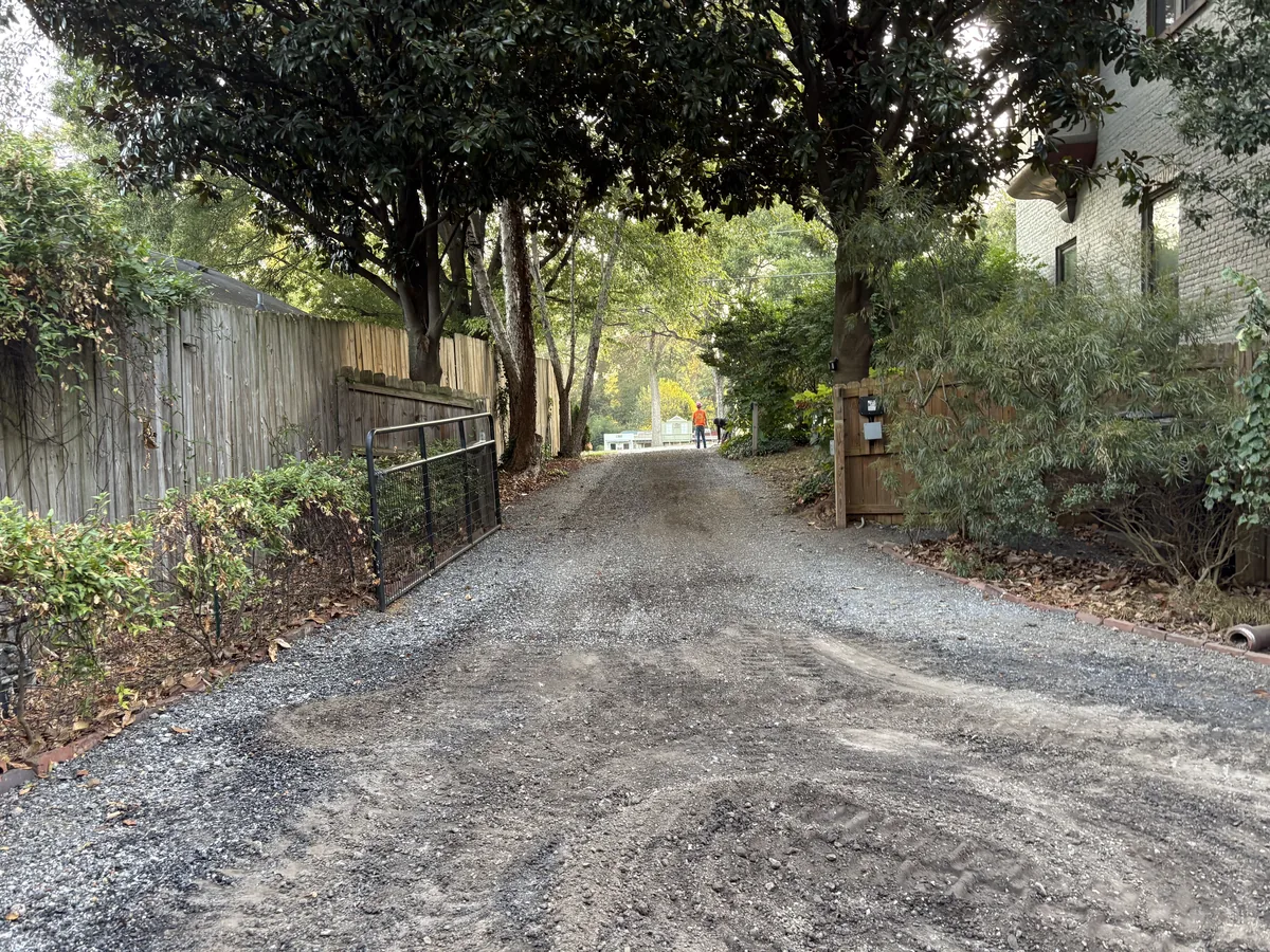 Graded and compacted stone base ready for a new asphalt surface between board fences